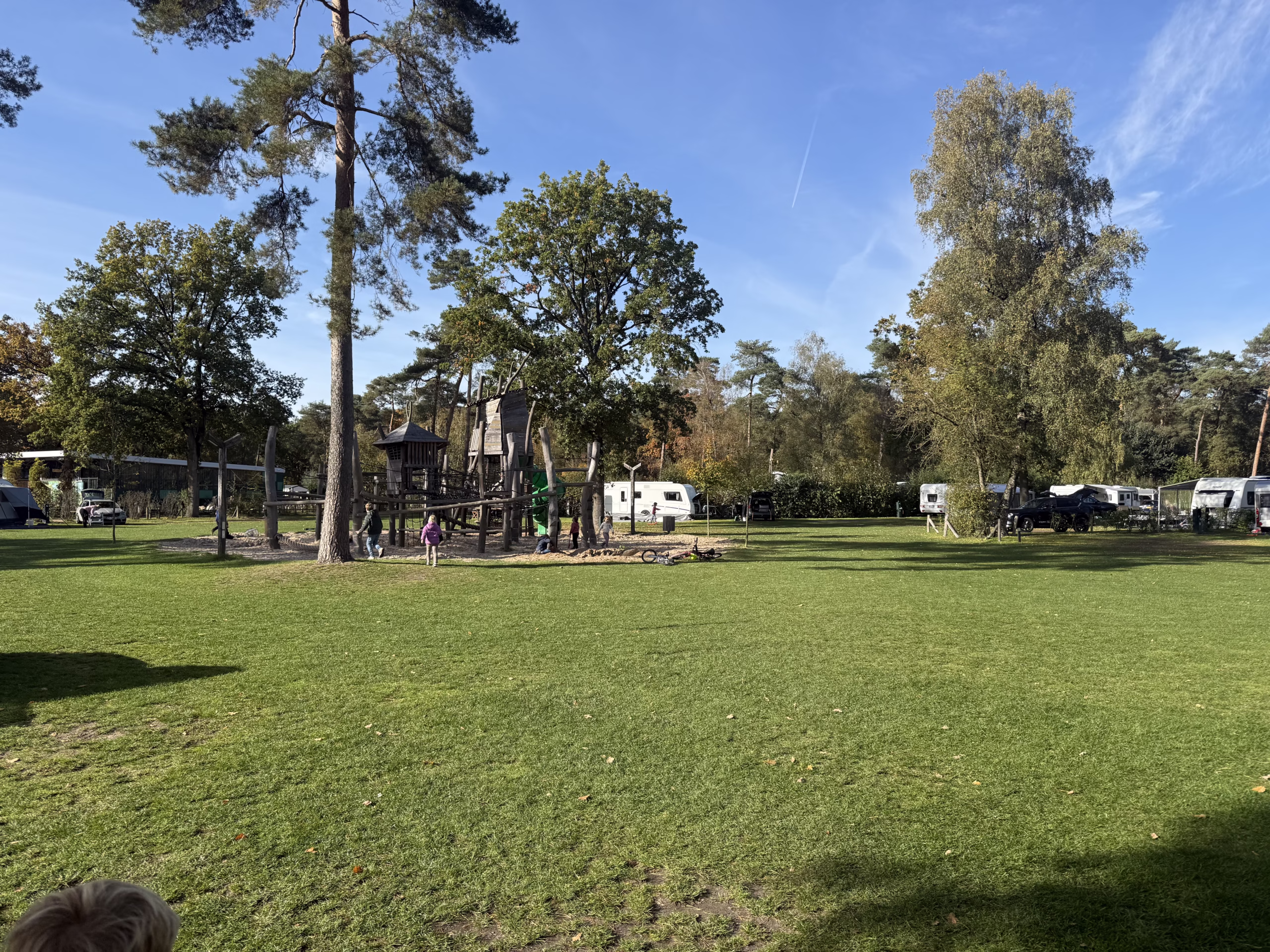 Overzicht van kampeerveld met speeltoestel en caravans eromheen