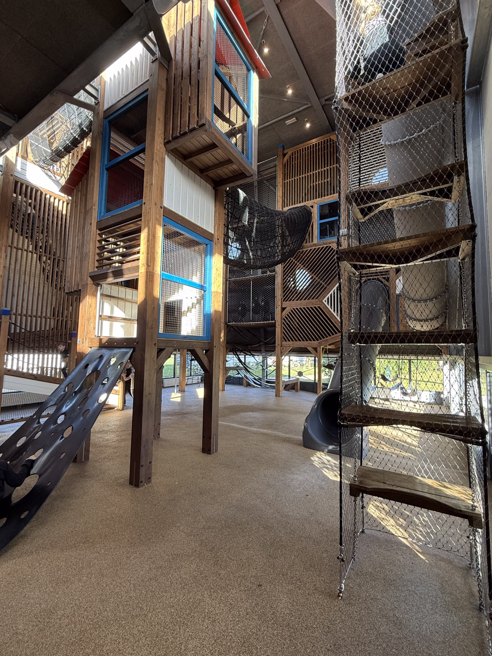 Binnenspeeltuin met netten, houten elementen en glijbaan