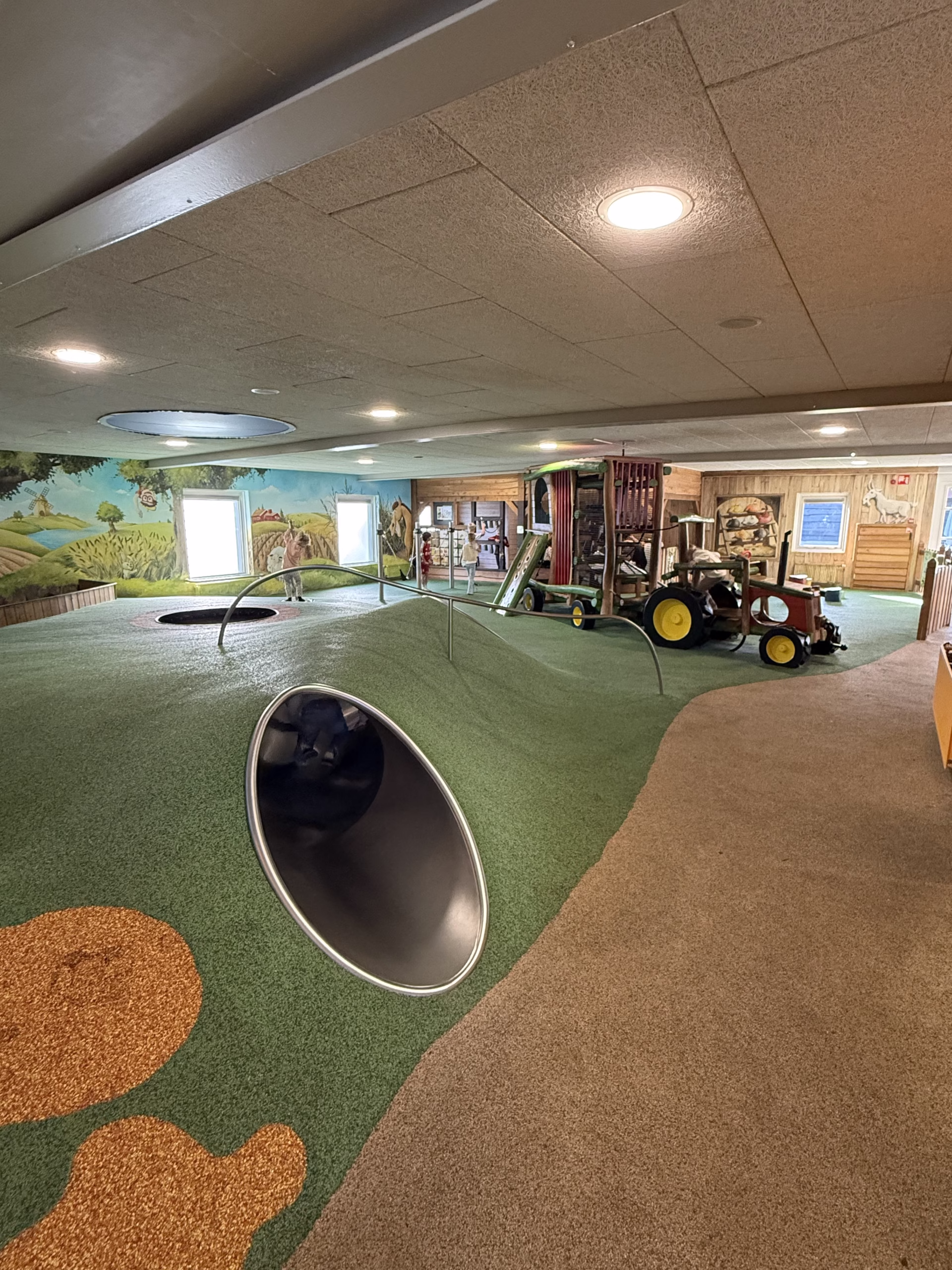 Kinderzone met zachte heuvels, buisglijbaan en tractor